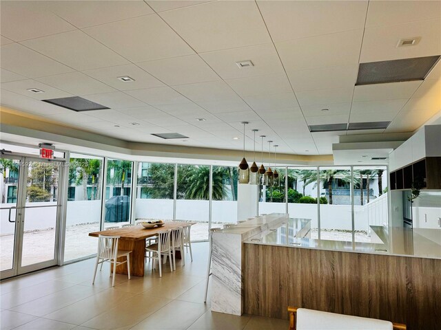 interior space with light stone countertops, light tile patterned floors, decorative light fixtures, and a healthy amount of sunlight