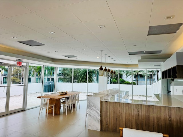 kitchen with light stone counters, pendant lighting, a paneled ceiling, visible vents, and modern cabinets