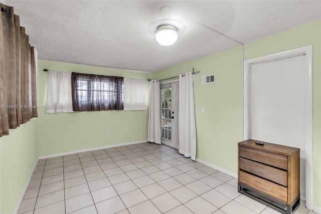 tiled spare room featuring a textured ceiling