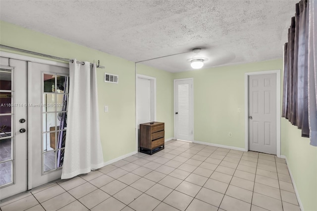 empty room with ceiling fan, light tile patterned floors, a textured ceiling, and french doors