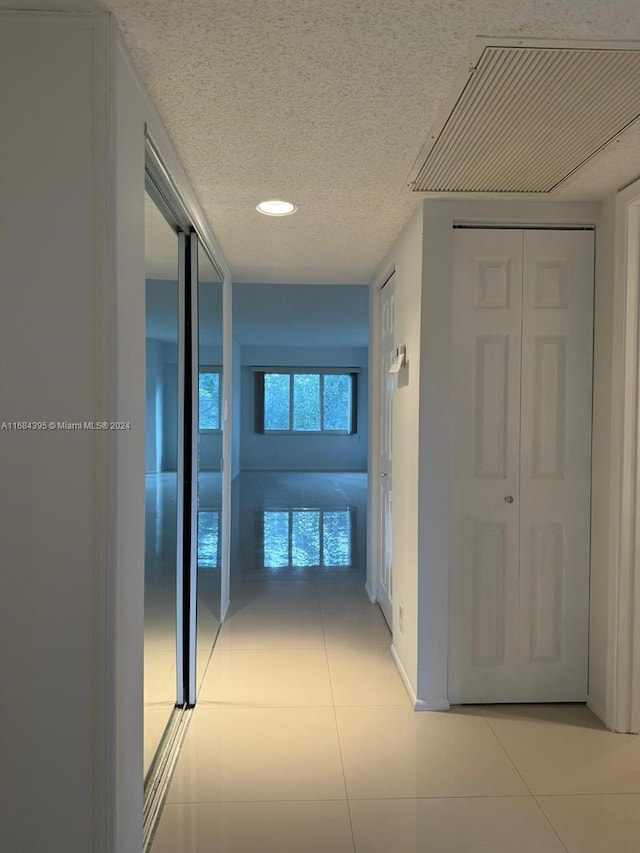 hall featuring light tile patterned floors and a textured ceiling