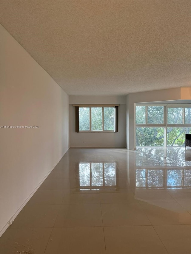 tiled empty room featuring a textured ceiling