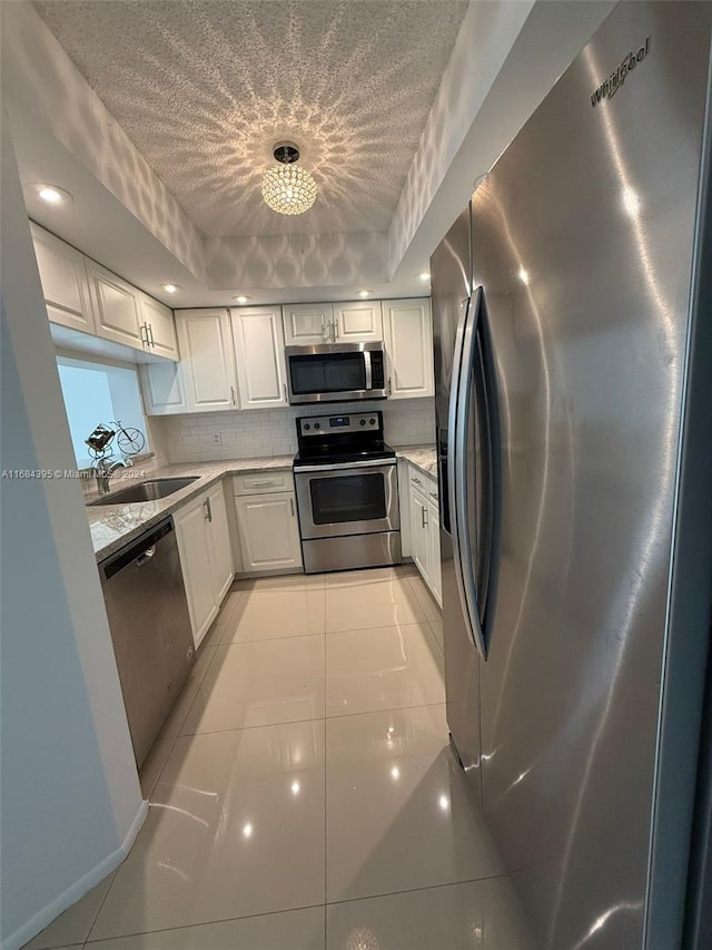 kitchen with white cabinets, sink, a raised ceiling, and stainless steel appliances