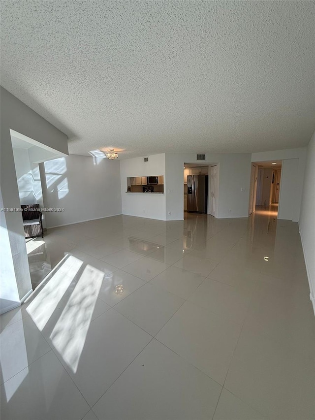 unfurnished living room featuring tile patterned flooring and a textured ceiling