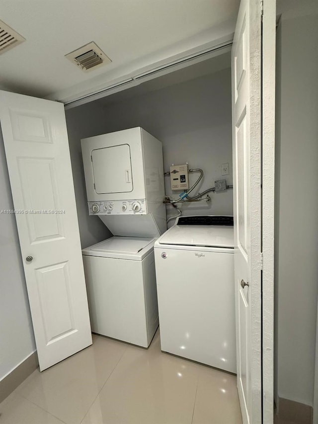 laundry area with light tile patterned floors and stacked washer and clothes dryer