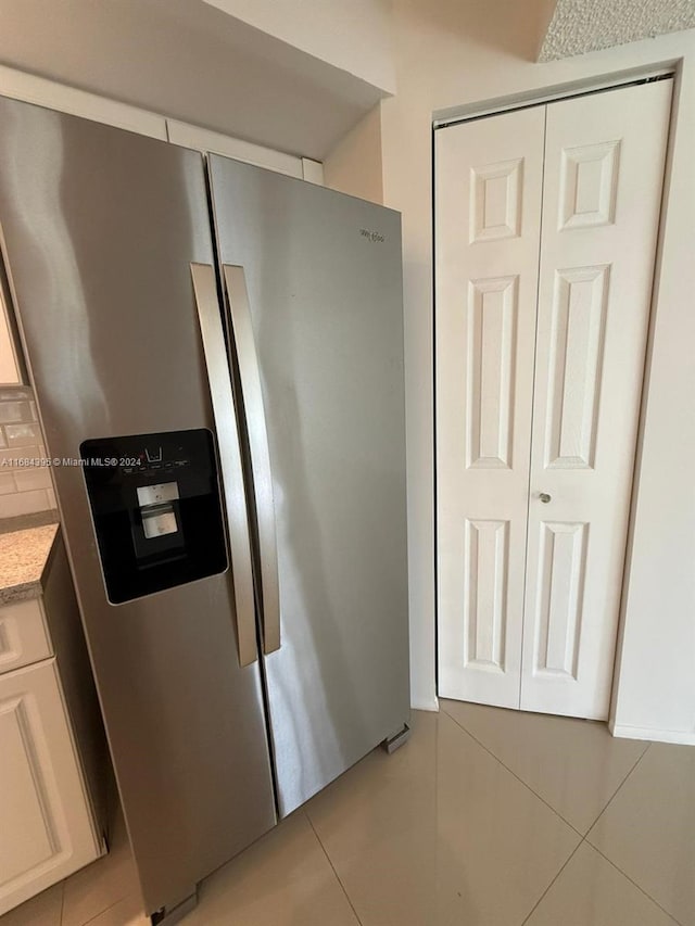 kitchen with white cabinets, stainless steel fridge with ice dispenser, and light tile patterned floors