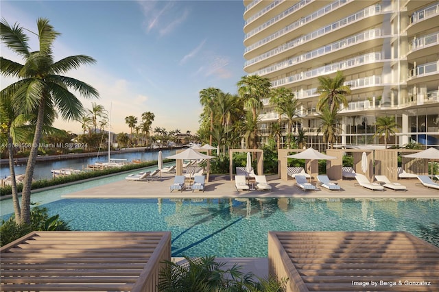 pool at dusk with a patio area and a water view