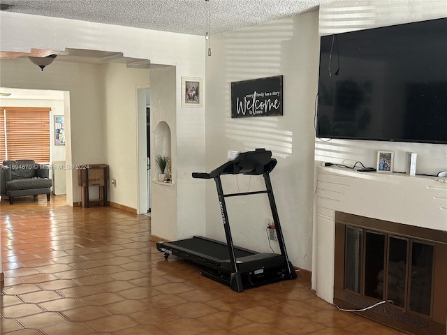 workout room with tile patterned flooring and a textured ceiling