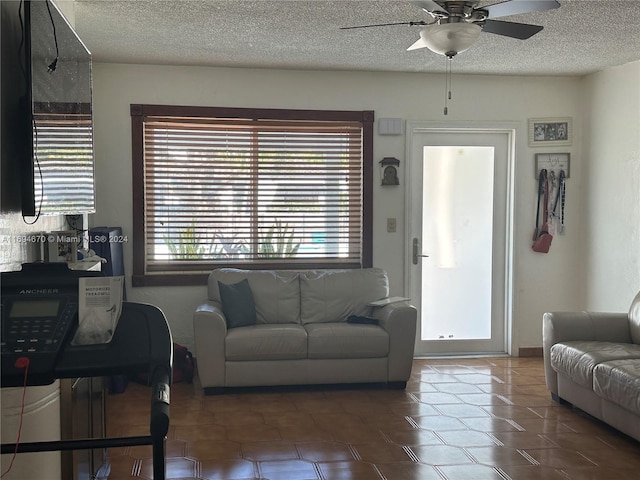 living room featuring a textured ceiling, dark tile patterned flooring, and ceiling fan