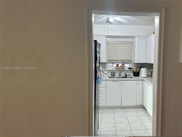 kitchen featuring tasteful backsplash, sink, white cabinets, and light tile patterned floors