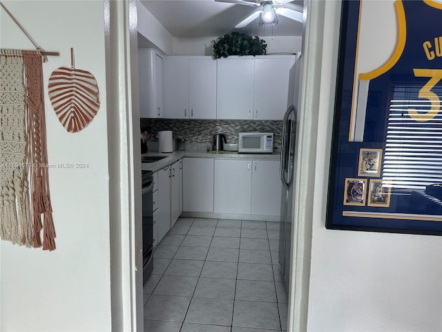 kitchen with white cabinets, decorative backsplash, light tile patterned floors, and black electric range oven