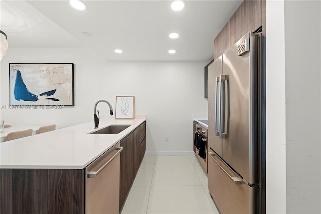 kitchen featuring kitchen peninsula, sink, light tile patterned floors, and stainless steel appliances