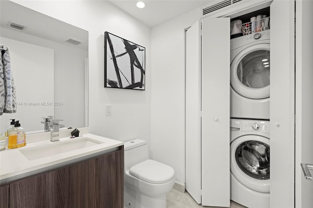 laundry room featuring light tile patterned floors, stacked washing maching and dryer, and sink