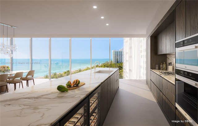 kitchen with dark brown cabinets, a water view, appliances with stainless steel finishes, and sink