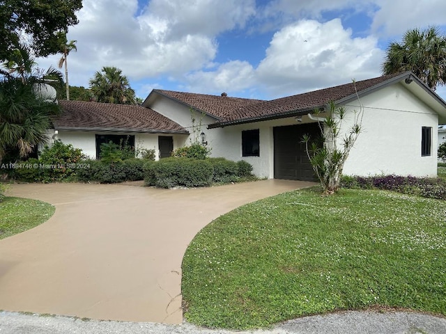 ranch-style house featuring a garage and a front lawn