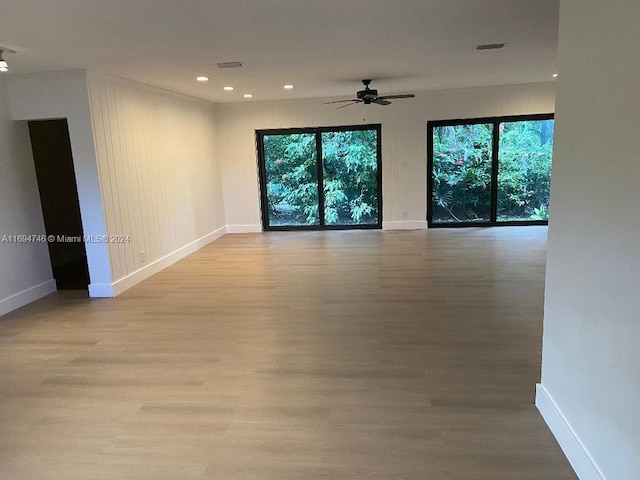 empty room with light wood-type flooring, a wealth of natural light, and ceiling fan