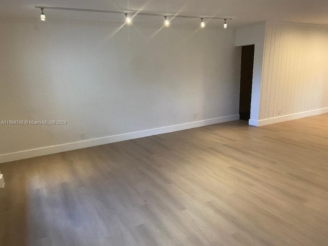 empty room with light hardwood / wood-style floors and rail lighting