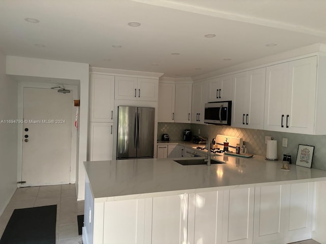 kitchen with kitchen peninsula, white cabinetry, light tile patterned floors, and appliances with stainless steel finishes