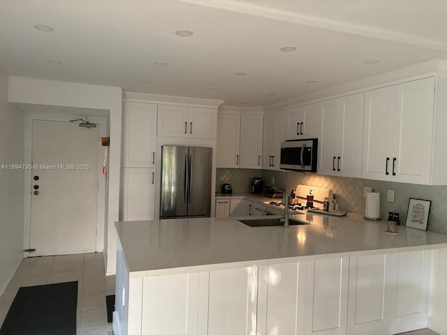 6884 N Kendall Dr Unit C407, Pinecrest, FL 33156 - kitchen featuring appliances with stainless steel finishes, a peninsula, light countertops, backsplash, and white cabinetry