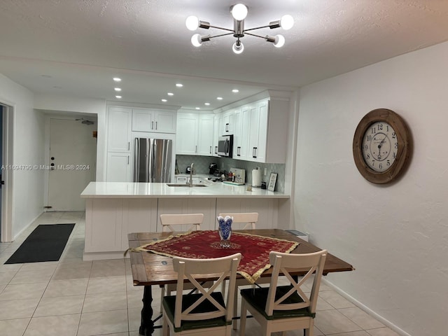 kitchen featuring backsplash, kitchen peninsula, a notable chandelier, white cabinetry, and stainless steel appliances