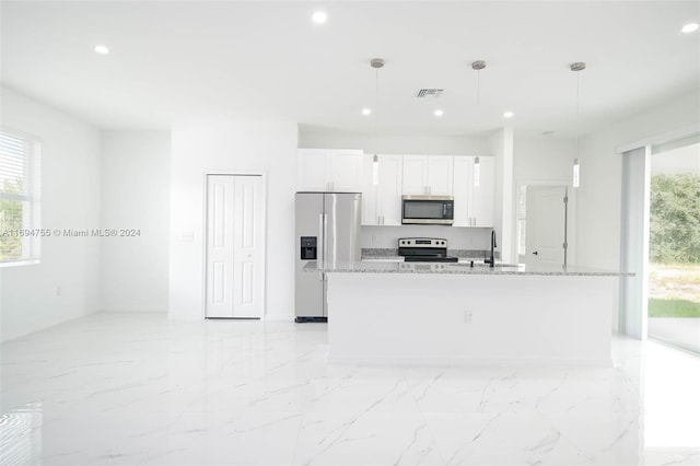 kitchen with appliances with stainless steel finishes, decorative light fixtures, white cabinetry, and a center island with sink