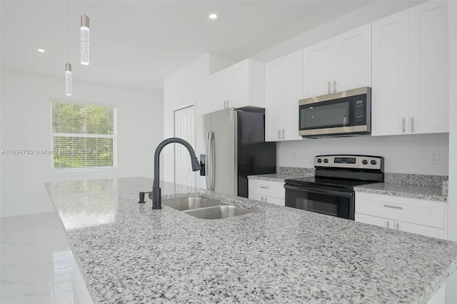 kitchen featuring appliances with stainless steel finishes, white cabinetry, hanging light fixtures, and an island with sink