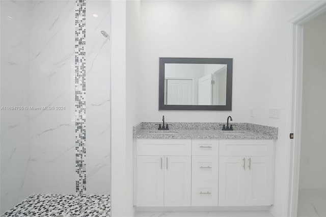 bathroom with tiled shower and vanity