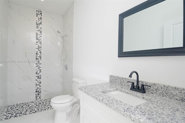 bathroom with a tile shower, vanity, and toilet