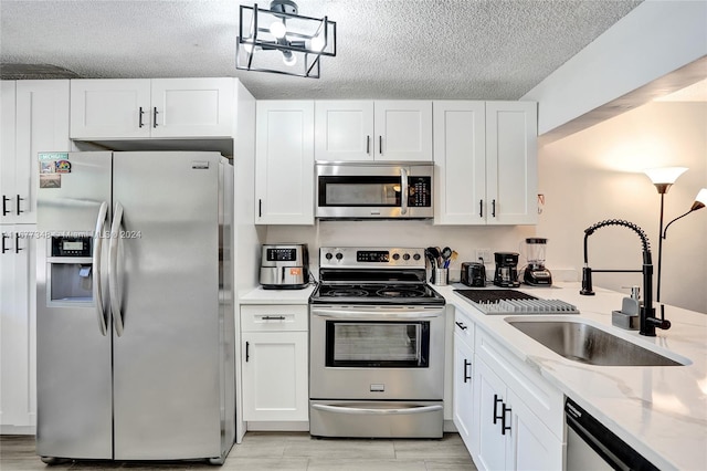 kitchen featuring light stone countertops, white cabinets, hanging light fixtures, and appliances with stainless steel finishes