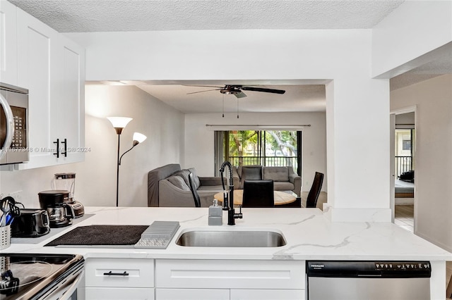 kitchen featuring light stone countertops, a textured ceiling, stainless steel appliances, sink, and white cabinetry