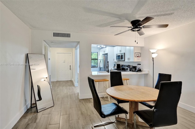 dining area featuring a textured ceiling, light hardwood / wood-style flooring, and ceiling fan