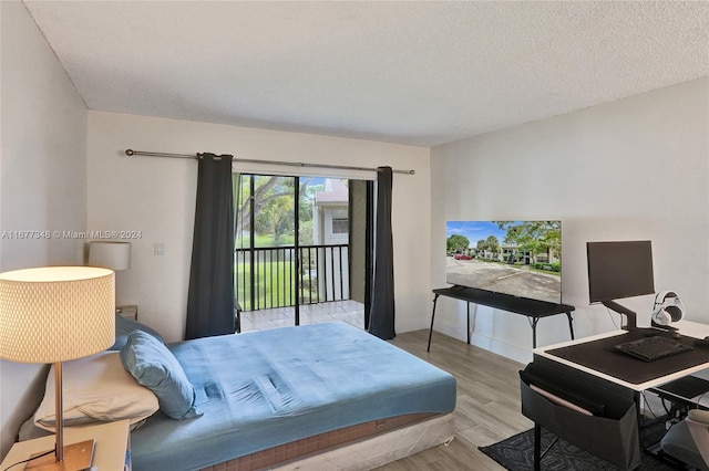 bedroom featuring access to exterior, a textured ceiling, and light wood-type flooring