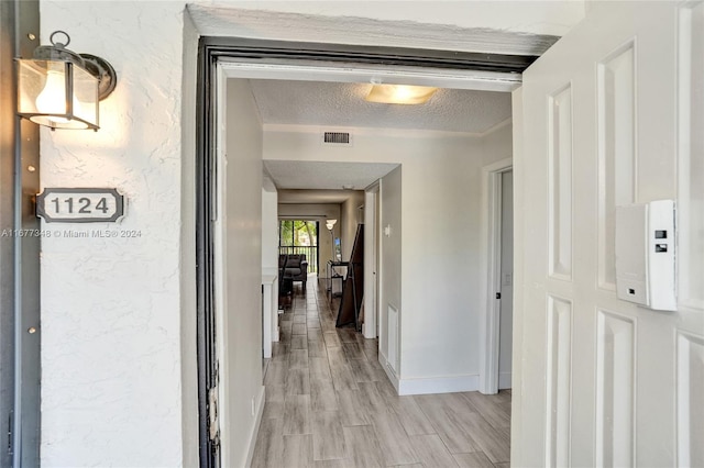 hall featuring a textured ceiling and light hardwood / wood-style floors