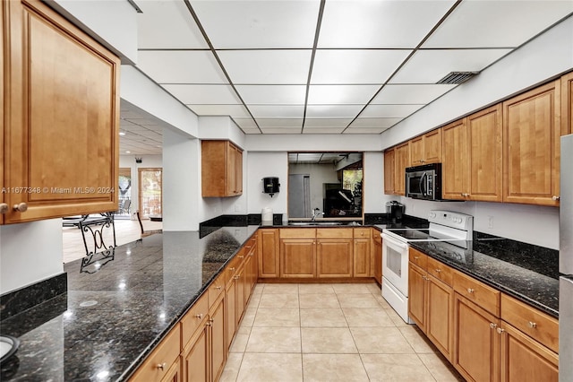 kitchen featuring a drop ceiling, sink, white range with electric stovetop, dark stone counters, and light tile patterned floors