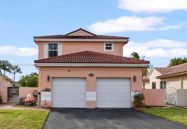 mediterranean / spanish house with a garage, a tile roof, driveway, a gate, and stucco siding