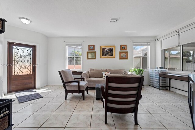 living room with a wealth of natural light, visible vents, and light tile patterned floors