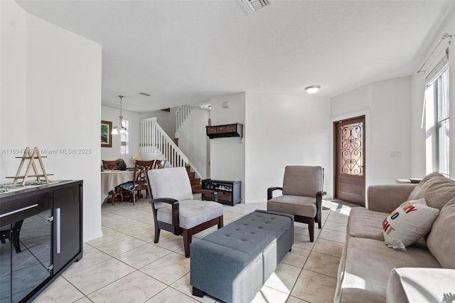 living area with stairs, light tile patterned flooring, and visible vents