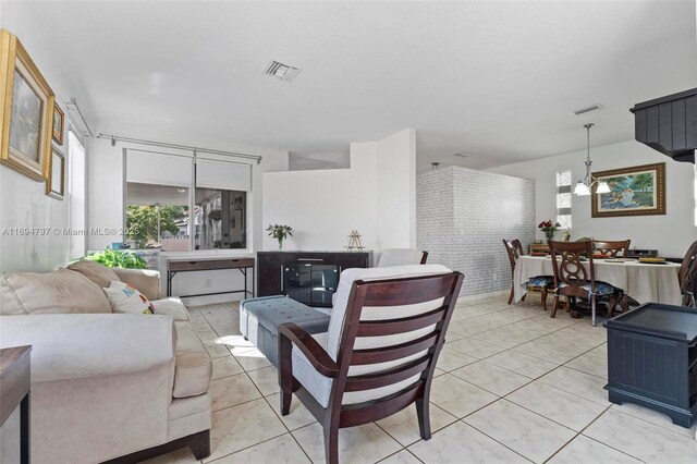 living room with light tile patterned floors, visible vents, and a notable chandelier