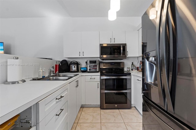 kitchen with stainless steel appliances, light countertops, light tile patterned flooring, a sink, and white cabinetry