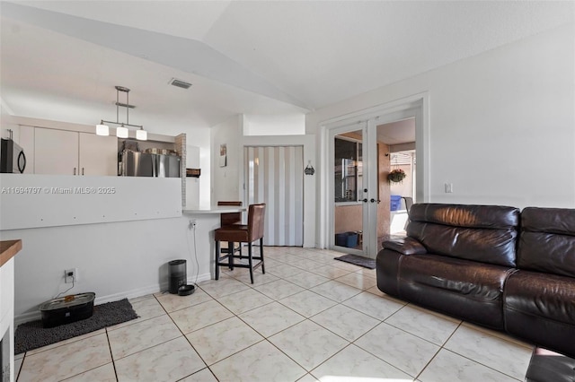 living area with visible vents, vaulted ceiling, french doors, and light tile patterned flooring