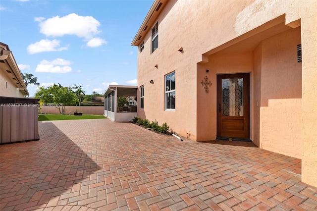 view of patio featuring fence and a sunroom