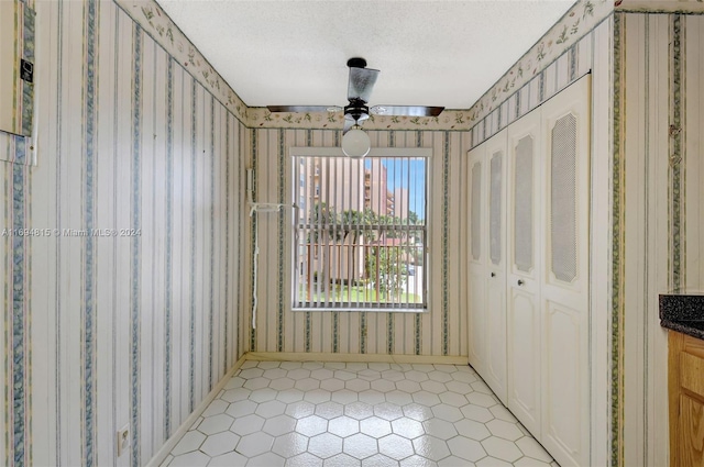 interior space with ceiling fan and a textured ceiling