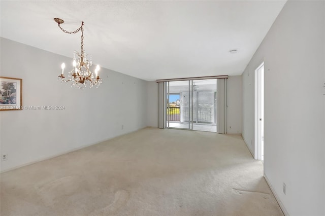 carpeted empty room featuring an inviting chandelier