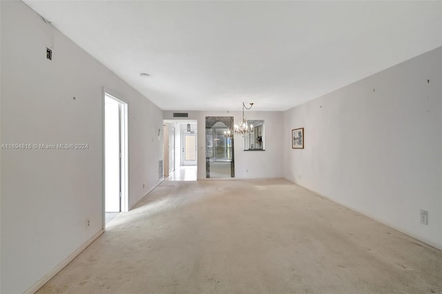 carpeted empty room featuring a notable chandelier