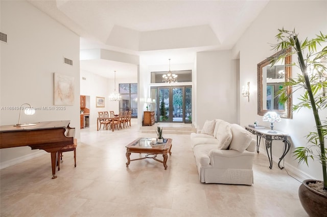 living room featuring a raised ceiling, a towering ceiling, and a chandelier