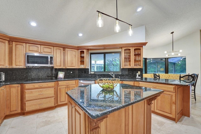 kitchen with decorative light fixtures, a center island, lofted ceiling, and appliances with stainless steel finishes