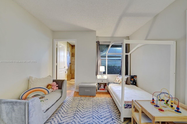 bedroom with connected bathroom, a textured ceiling, and light wood-type flooring