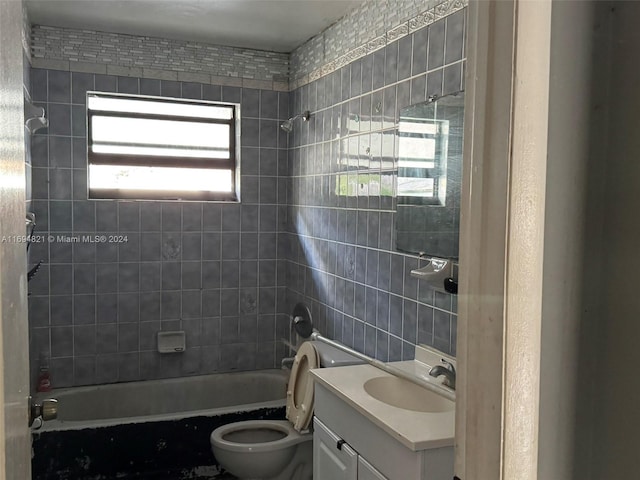 full bathroom featuring vanity, tiled shower / bath combo, and toilet