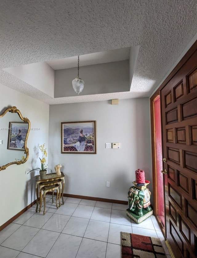 tiled foyer entrance featuring a raised ceiling and a textured ceiling