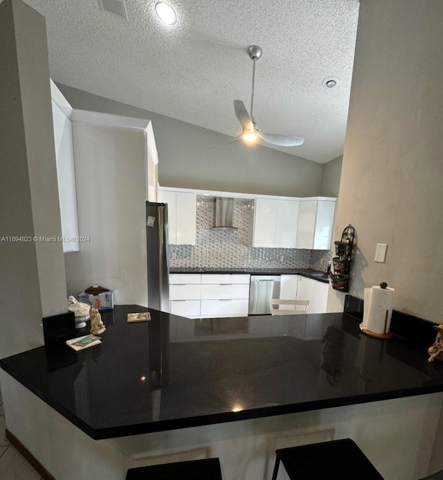 kitchen featuring lofted ceiling, white cabinetry, kitchen peninsula, and appliances with stainless steel finishes